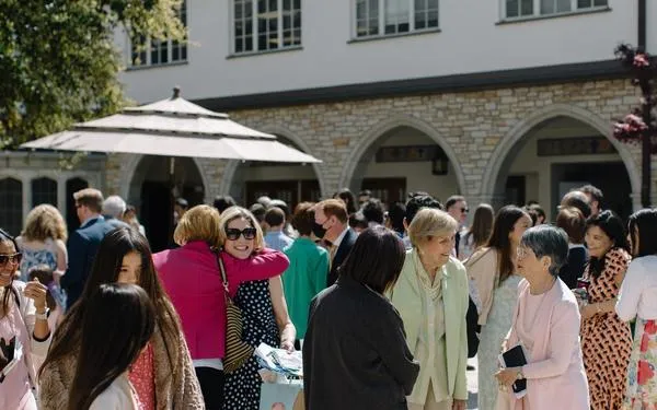 Groups of women in dresses greet one another in the courtyard at SMCC at mid-day.