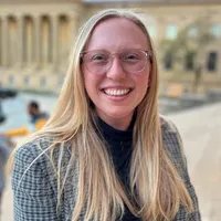A woman with blonde hair and glasses smiles. Head shot of Beth Putney.