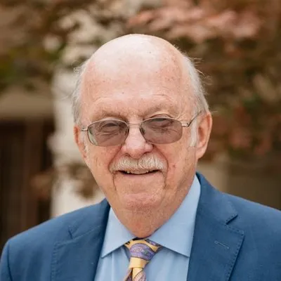 Rev. Dr. Ron C. White, Scholar in Residence. A smiling older gentleman in a blue suit.