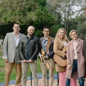 Members of the Virginia Road Band in coats and jackets stand with their instruments after an outdoor service.