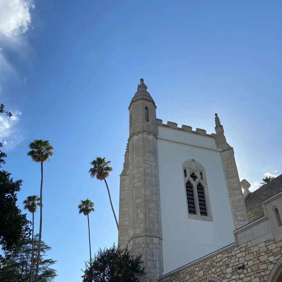 The bell tower at SMCC against a blue sky with palm trees in the background.